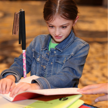 A young girl reads a Braille book.
